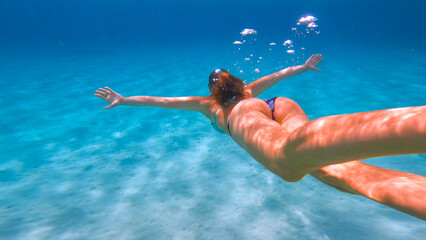 UNDERWATER: Striking visibility and clarity under the sea with a swimming woman. Active lady in...