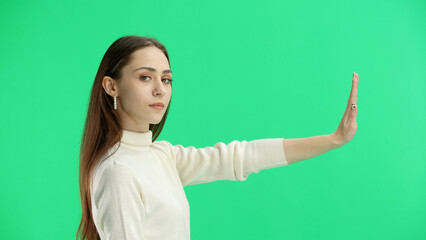 A woman, close-up, on a green background, shows a stop sign