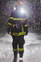 A determined female firefighter in a professional uniform striding through the dangerous, rainy...