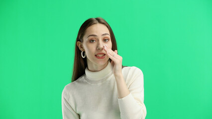 A woman, close-up, on a green background, tells a secret