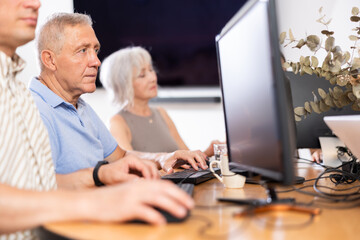 Side view of elderly people while studying in computer class in nursing home