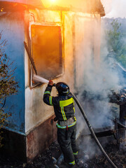 Firefighter extinguish fire in house using spraying hose