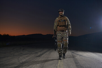 A professional soldier in full military gear striding through the dark night as he embarks on a...