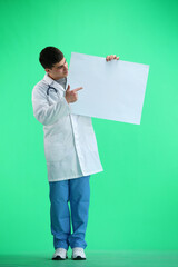 The doctor, in full height, on a green background, shows a white sheet