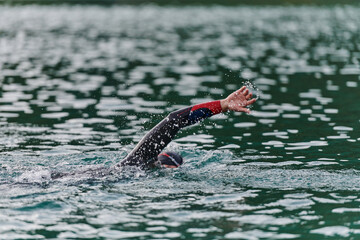A professional triathlete trains with unwavering dedication for an upcoming competition at a lake,...