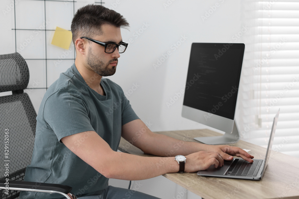 Poster young programmer working at desk in office