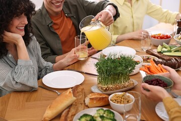 Friends eating vegetarian food at wooden table indoors