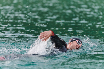 A professional triathlete trains with unwavering dedication for an upcoming competition at a lake,...