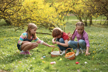 Easter celebration. Cute little children hunting eggs outdoors