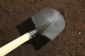 Metal shovel on fertile soil, top view. Gardening tool
