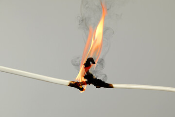 Electrical wire burning on light background, closeup