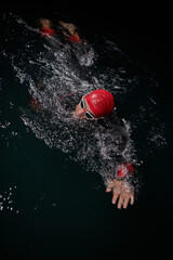 A determined professional triathlete undergoes rigorous night time training in cold waters,...