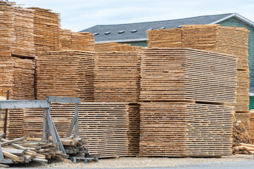 A lumber yard of a hardware store with bulk stacks of short-cut lumber, boards, and rough planks stockpiled for sale. The timber yard has sprucewood sawed for building materials and stacked for sale.