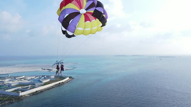 Couple on island Vacation Taking selfie while Parasailing Over Sky Blue Sea, Drone Follow