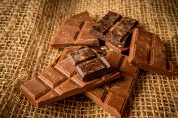 Light and dark chocolate pieces on a rustic background