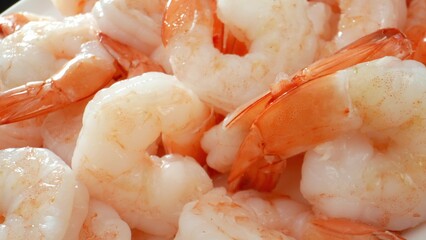 Frozen shrimp: translucent or semi-translucent flesh, slight pink hue. Segmented body, curved tail. Size varies by species, processing. Food concept. Shrimp background. 
