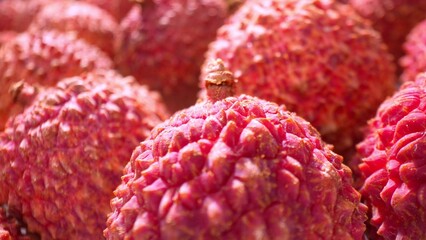 Zooming in, the camera unveils the rugged elegance of lychee skin. Its vibrant red hue contrasts...