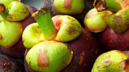 Dive into the intricate world of mangosteen with this macro shot. Rich, velvety purple skins, crowned by vibrant green calyxes, invite you to savor the exotic allure of this tropical gem.
