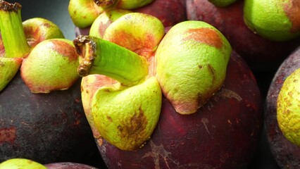 Macro lens captures the allure of mangosteen, its deep purple rind juxtaposed with vibrant green...
