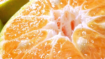 Glistening green oranges split open, unveiling their succulent orange flesh dotted with seeds, a...