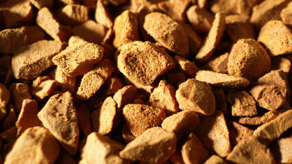 Dive into a mesmerizing close-up of freeze-dried coffee granules, revealing their rugged, uneven texture. The rich, golden-brown hue hints at an intense flavor preserved within.
