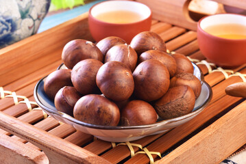 Obraz premium Roasted chestnuts on the plate served with Chinese tea. 