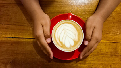view of latte coffee in red cup isolated on wooden table background.