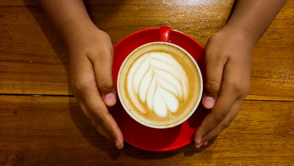view of latte coffee in red cup isolated on wooden table background.