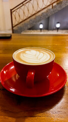 view of latte coffee in red cup isolated on wooden table background.