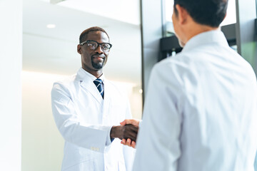 Multinational group in white coats shaking hands in a lobby