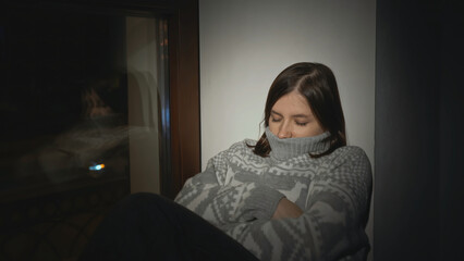 Young woman with anxiety disorder on window. Media. Young woman in sweater is sitting on horse with...