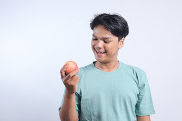 Smiling Young Asian Male Holding And Looking Apple Isolated On White Background