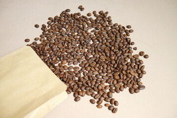 Coffee Beans Spill Out From Packaging  Isolated On Beige Background