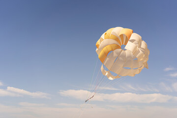 The parachute is fully inflated, showcasing vivid yellow and white colors as it glides through the...