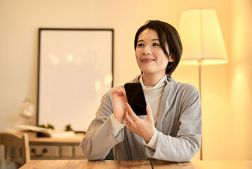 部屋でスマートフォンを操作する女性