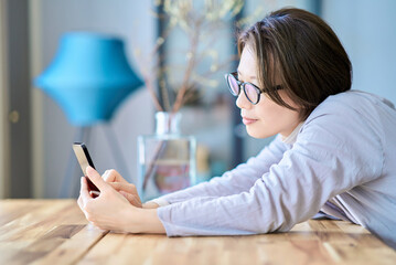 疲れた様子でスマートフォンを操作する女性