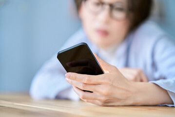 疲れた様子でスマートフォンを操作する女性