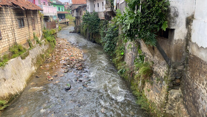 polluted small river in densely populated city in Asia, dirty water with trash, plastic and garbage, slum area