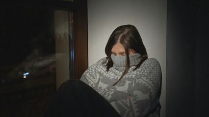 Young woman with depression at window of house. Media. Young woman in sweater is sitting on window. Single woman with depression falls asleep on window of house at night