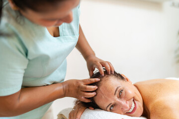 Latin masseur massaging the head of a relaxed happy woman