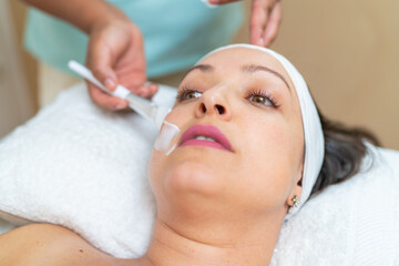 Dermatologist applying facial cream for peeling to a woman