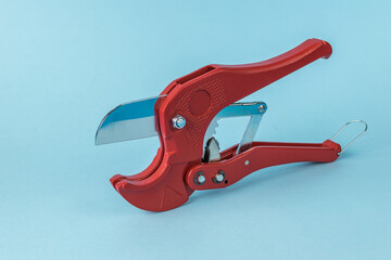 Red Pipe Cutter Tool on Blue Background - Close-up of Plumbing Equipment