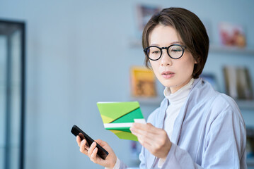 困った表情で銀行口座の通帳を見る女性