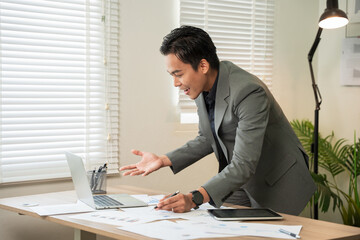 Asian businessman working on computer looking at documents at office.