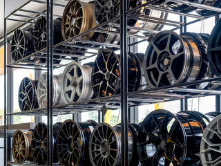 Scene of modern tyre store decoration with various designs of steel alloy wheels rim on metal shelf...