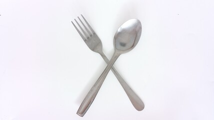 crossed spoon and fork made of stainless steel on a white background