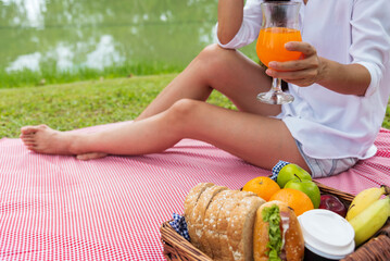 Close up Women picnic in green park hands holding glass of orange juice fresh fruit cool summer....
