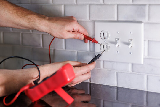 Electrician testing electrical outlet with multimeter