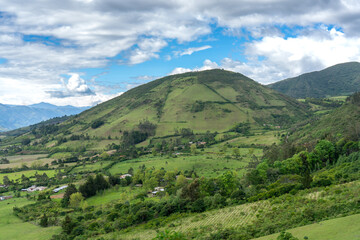 Obraz premium Aerial view of agricultural fields between houses in a Colombian landscape with mountains.