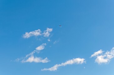 A plane is flying in a blue sky with clouds